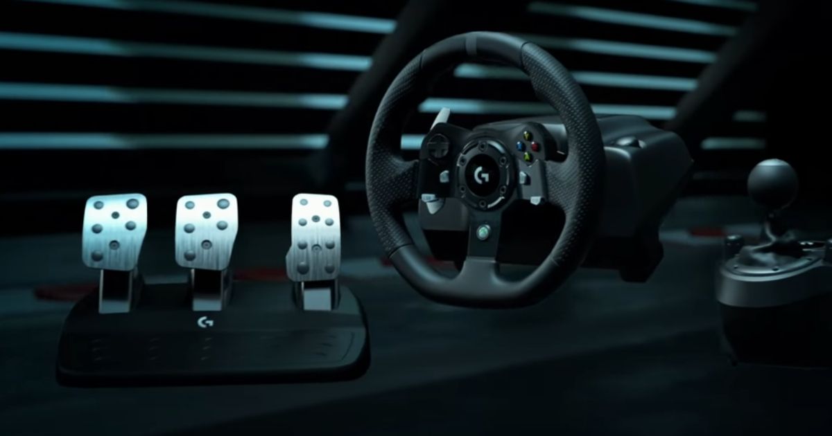 A black sim racing wheel in a dark room next to a set of black and silver pedals and a black shifter.