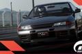 Gran Turismo 7 in-game image of someone in a white helmet racing a dark grey GT-R.