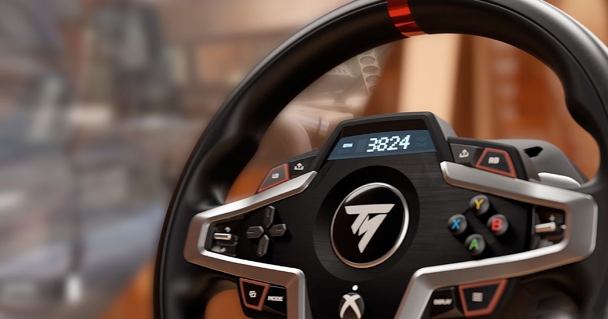 Close-up of a black racing wheel with a digital display, a red central line, and silver trim.