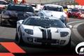 In-game Gran Turismo 7 image of a white Ford GT featuring black racing stripes leading a pack of cars.