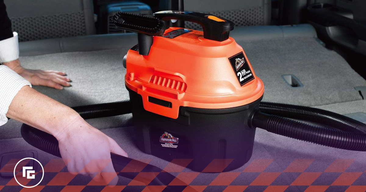 Image of an orange and black vacuum cleaner being used in a car.