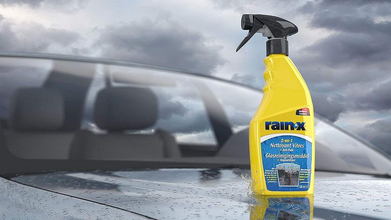 A yellow bottle with a black spray cap and blue branding sat on the bonnet of a car.