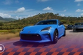 Forza Horizon 5 in-game image of a blue Toyota racing against a black and grey car behind.