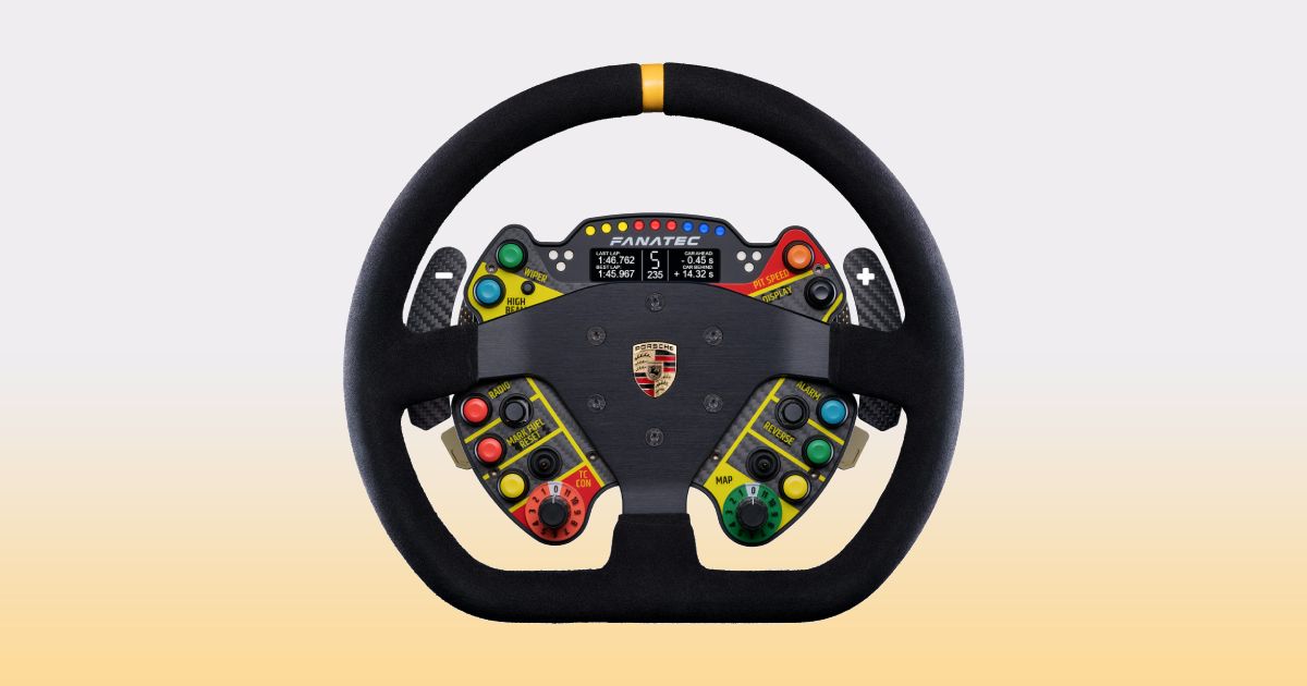 A black suede racing wheel with a multicoloured console behind it, an orange central line at the top, and the Porsche badge in gold, black, and red in the center.
