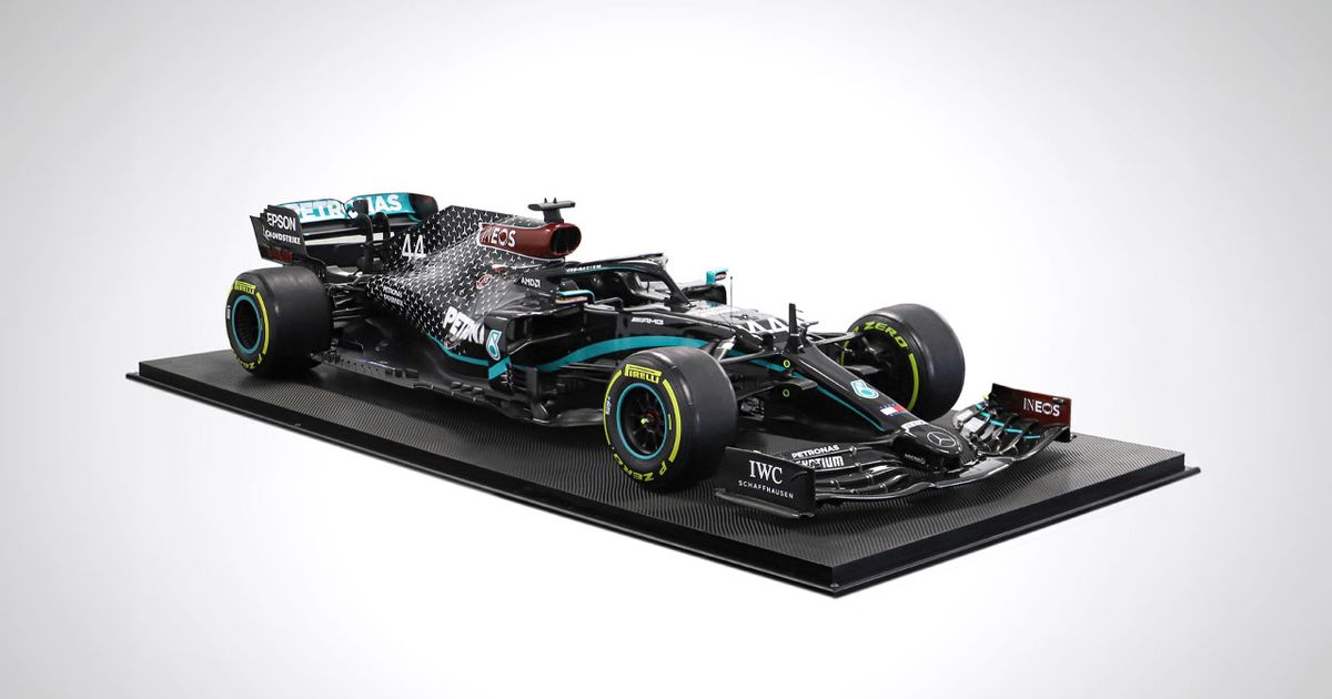 A model of the black and light blue Mercedes F1 car on a black podium.
